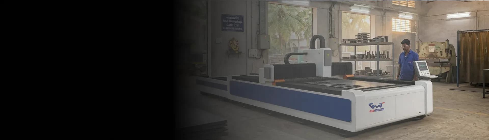 Operator monitoring a high-power industrial fiber laser cutting machine on a South Indian factory floor.